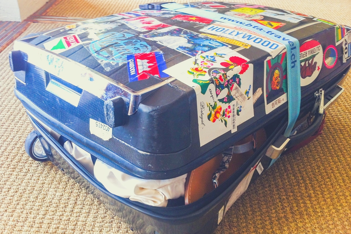 Überfüllter blauer Koffer mit vielen Stickers - Packen für die ganze Familie – 5 Tipps