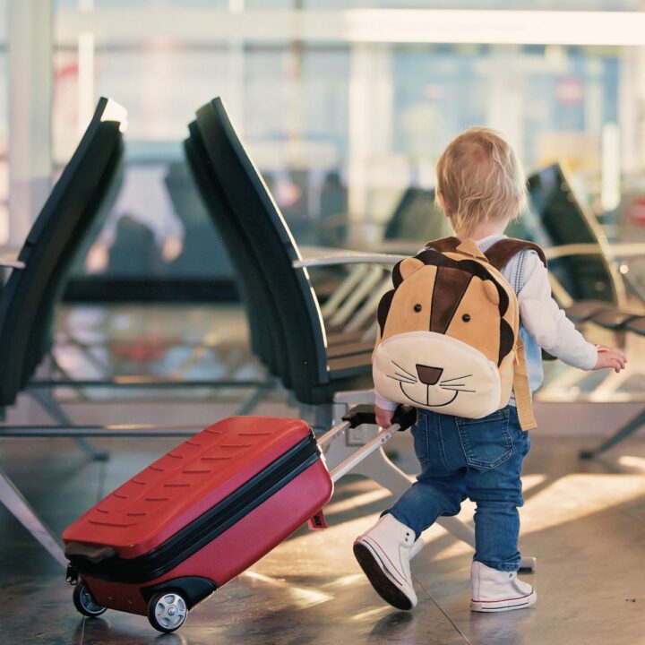 Kleinkind am Flughafen mit Köfferchen. Was muss man alles beachten beim Fliegen mit Baby und Kleinkind?