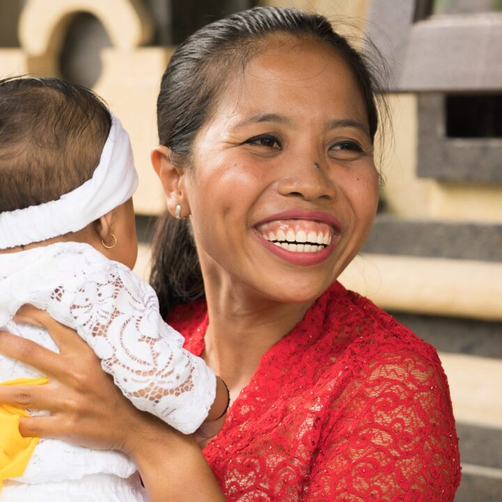 Balinesische Taufe Frau mit roter Bluse und Baby