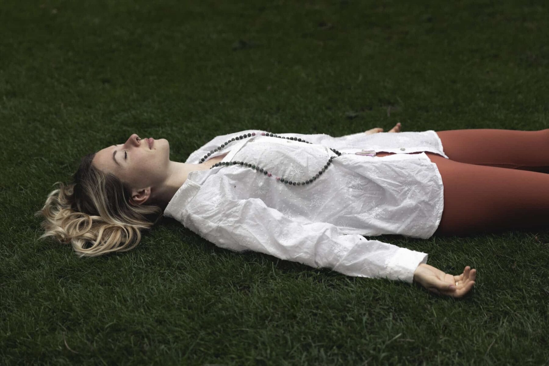 Die Journalistin Nadija Brenneisen liegt mit geschlossenen Augen auf einer Wiese - sie sagt: "Yoga Nidra hat mir das Leben gerettet!"