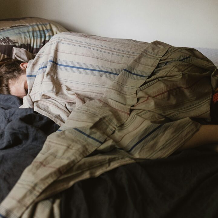 Frau liegt im Bett, fest eingewickelt in eine Decke. - sexualisierte Gewalt ist noch immer ein Tabuthema