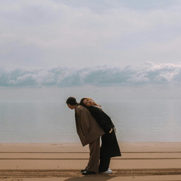 zwei Personen im Sand stehend, die sich aufeinander abstützen. Ist Monogamie wirklich die passende Beziehungsform, die glücklich macht?