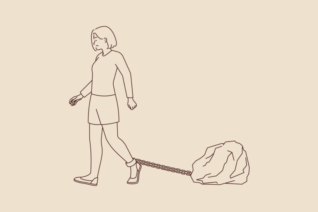 Frau mit Felsbrocken an einer Kette um ihren Fuss. - Sexismus und Diskriminierung am Arbeitsplatz: Eingesperrt in die Mütter-Schublade