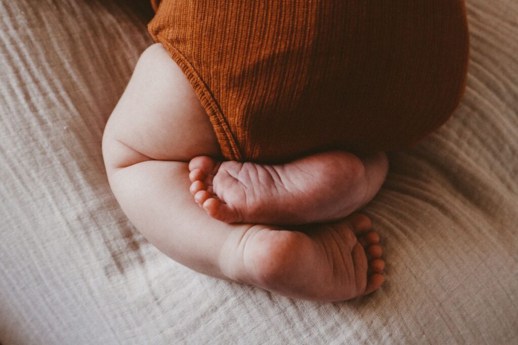 Baby liegt im Bett. Das Baby kann an Verstopfungen leiden.
