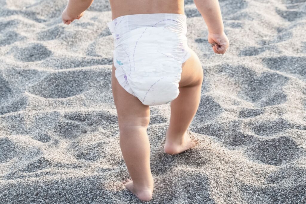 Kind läuft am Strand. Madenwürmer bei Kinder bemerkt man unter anderem durch Juckreiz.