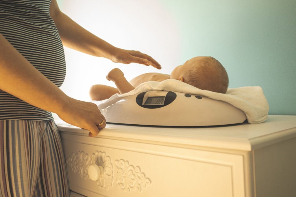 Baby auf einer Waage. Das Gewicht der Neugeborenen soll im Auge behalten werden.