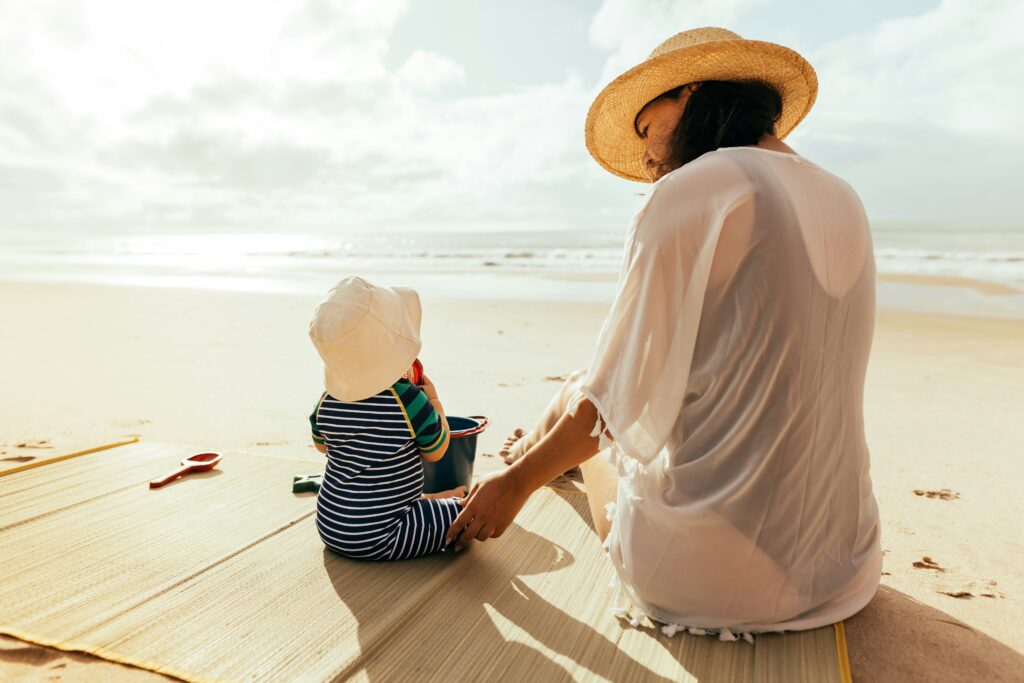 Mutter und Baby am Strand mit Sonnenschutz