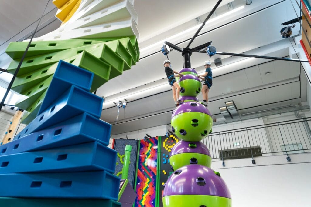 Zwei KInder auf farbigen Kletterelementen im Clip'n Climb-Bereich des Appenzeller Parks. - Ostschweiz mit Kindern bei Regen