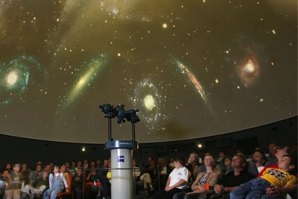 Zuschauer betrachten das Kuppeldach des Bodensee Planetariums. In der Mitte sieht man den Sternenprojektor. - Ostschweiz bei Regen