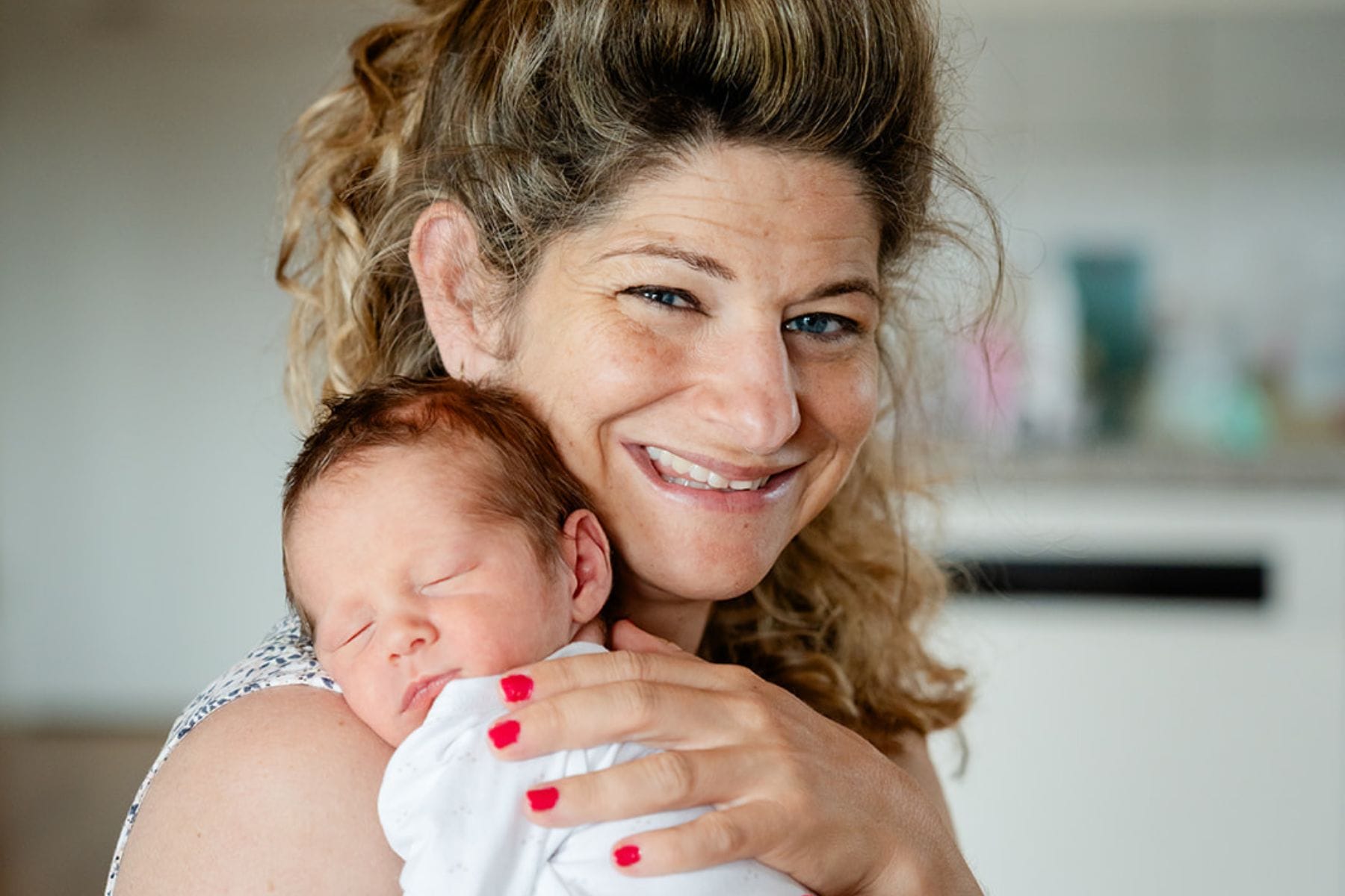 Strahlende Mutter mit schlafendem Baby auf dem Arm - Regenbogenbaby Lino bringt neues Vertrauen, aber die Trauer um Sternenkind Ennio bleibt
