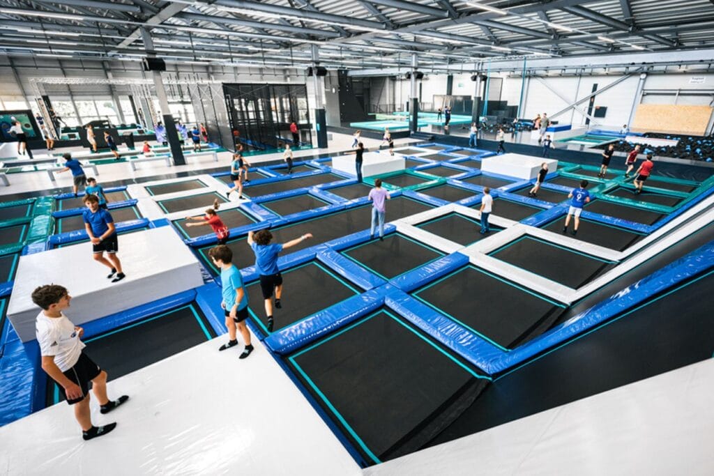 Blick in eine riesige Trampolinhalle mit hüpfenden Kindern. – Erprobte Tipps für Indoor-Ausflüge in der Ostschweiz mit Kindern bei Regen