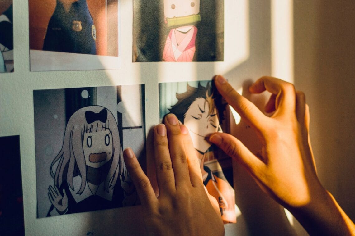Nahaufnahme von Kinderhänden, die gerade Manga-Bilder an eine Wand hängen. - Ein Guide für Eltern durch die Welt von Manga und Anime
