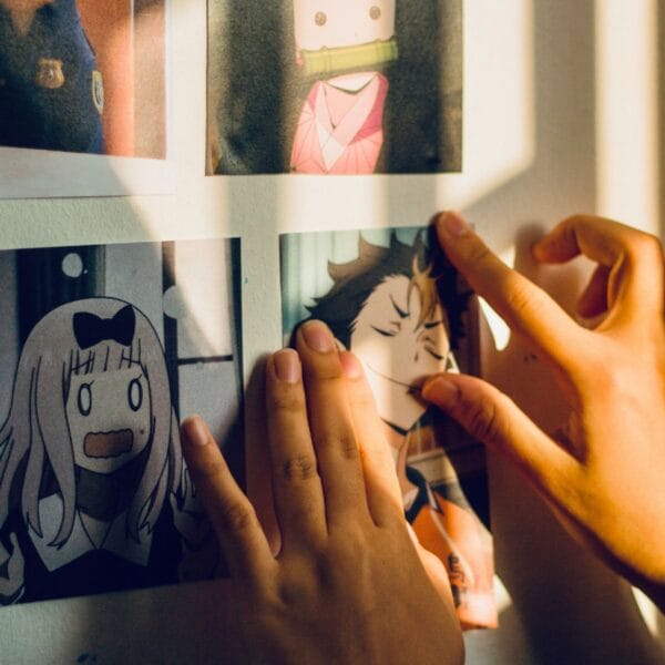 Nahaufnahme von Kinderhänden, die gerade Manga-Bilder an eine Wand hängen. - Ein Guide für Eltern durch die Welt von Manga und Anime