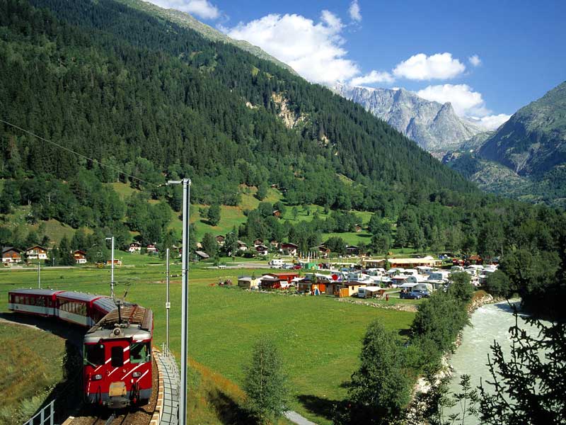 Camping Eggishorn in Fiesch, eingebettet zwischen Gletscherbach, bewaldeten Hügeln und den Bahngleisen. Beste Campingplätze für Familien