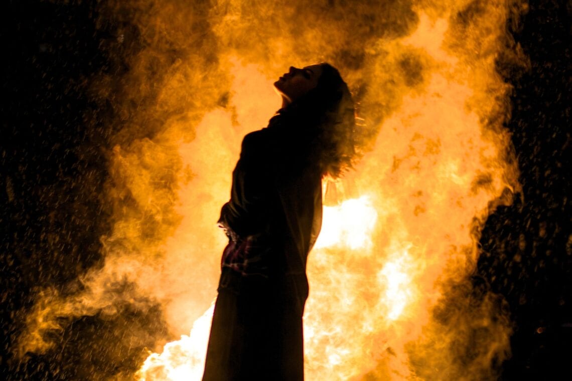 Silhouette einer Frau, die nach oben blickt. Hinter ihr ein explodierendes Feuer vor schwarzem Hintergrund. Erfahrungsbericht Wut-Seminar